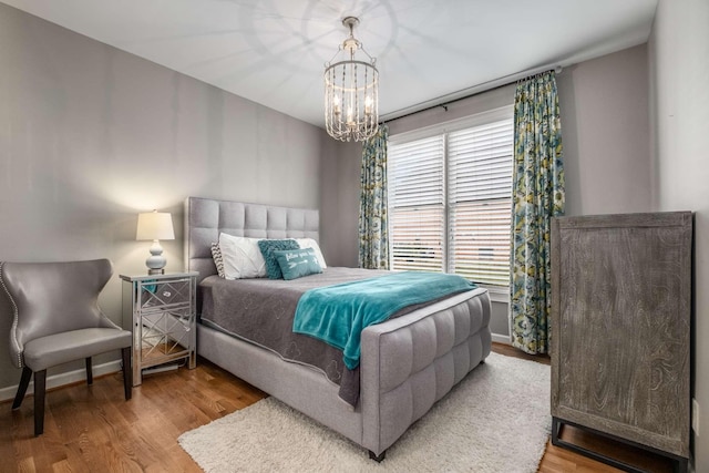 bedroom with a notable chandelier, wood finished floors, and baseboards