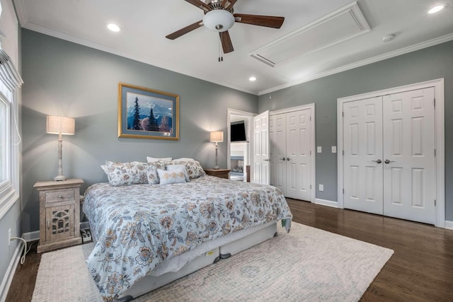 bedroom featuring crown molding, baseboards, multiple closets, attic access, and wood finished floors