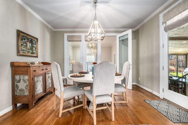 dining space with hardwood / wood-style flooring, crown molding, and an inviting chandelier