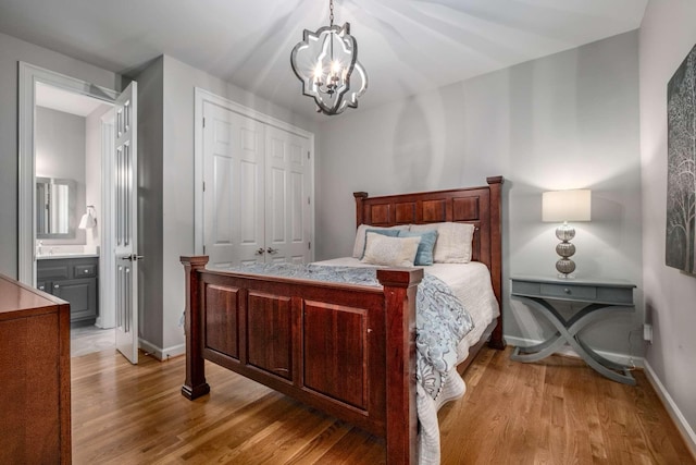 bedroom with connected bathroom, light hardwood / wood-style flooring, a chandelier, and a closet