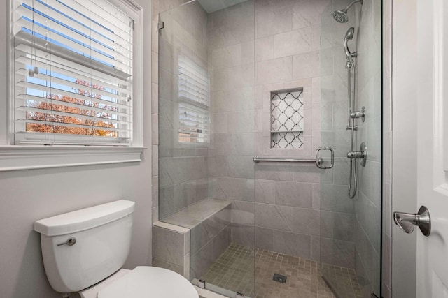 bathroom featuring toilet and a shower with shower door