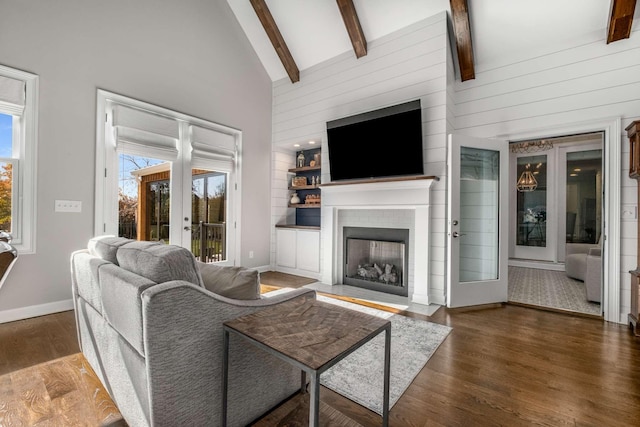 living area featuring french doors, beam ceiling, high vaulted ceiling, and wood finished floors