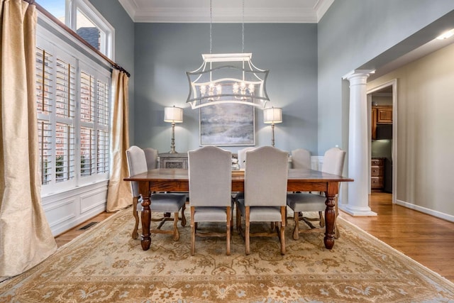 dining area with hardwood / wood-style flooring, ornamental molding, decorative columns, and a wealth of natural light