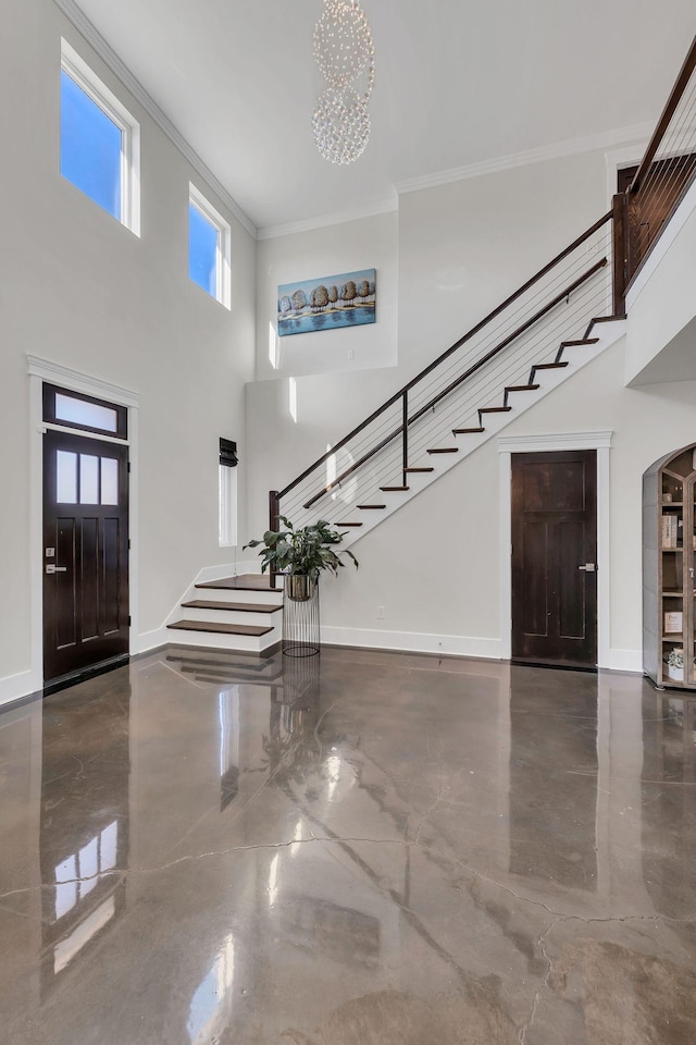 entryway featuring crown molding, a notable chandelier, and a high ceiling