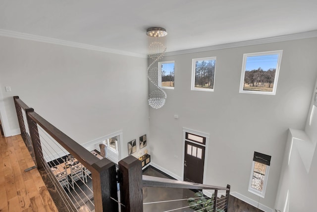 staircase featuring hardwood / wood-style floors, crown molding, plenty of natural light, and a notable chandelier