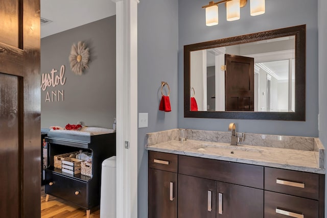 bathroom with vanity, crown molding, and wood-type flooring