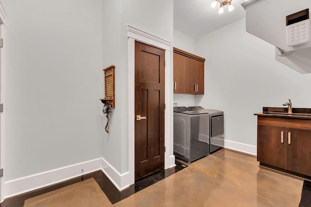 clothes washing area with sink, washer and clothes dryer, and cabinets