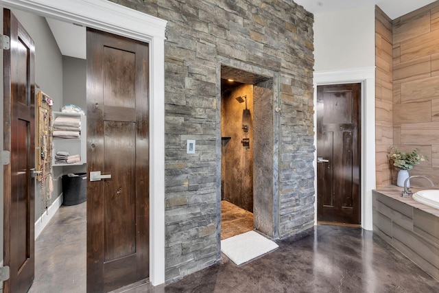 bathroom featuring wooden walls, concrete flooring, and a washtub