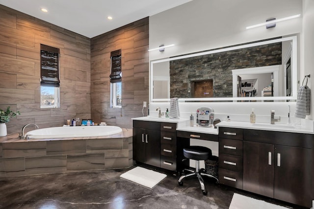 bathroom with vanity, tiled bath, and tile walls