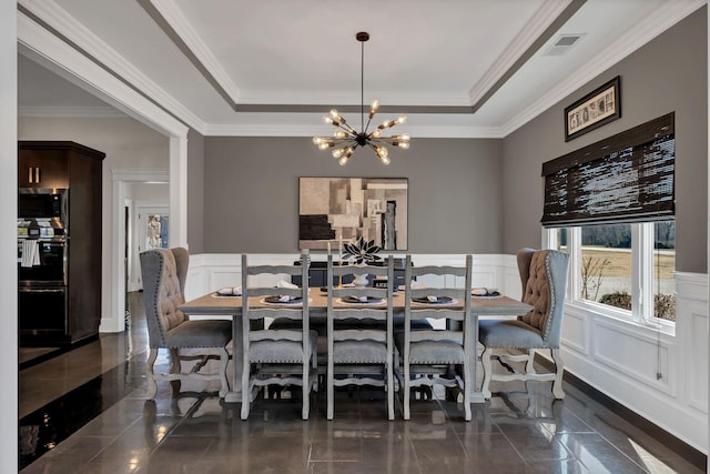 dining space featuring an inviting chandelier, ornamental molding, and a raised ceiling