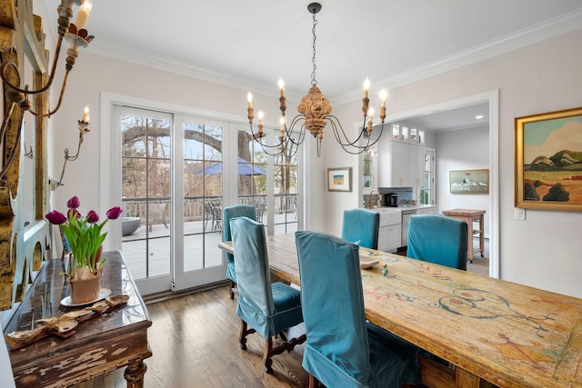 dining room with ornamental molding, dark hardwood / wood-style floors, sink, and a notable chandelier