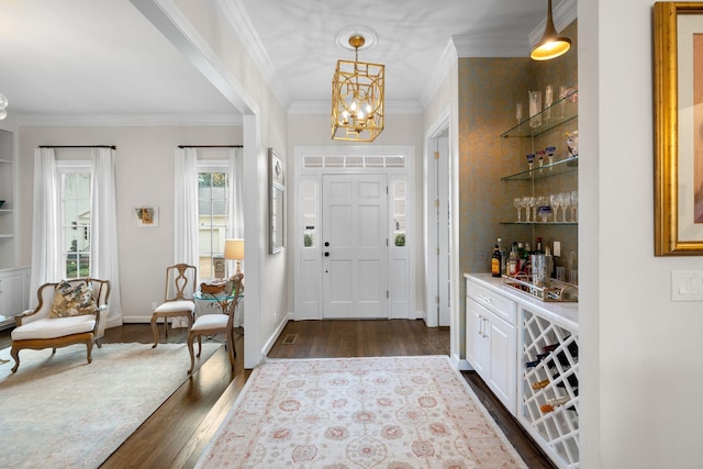 foyer featuring dark hardwood / wood-style flooring, crown molding, a chandelier, and bar area