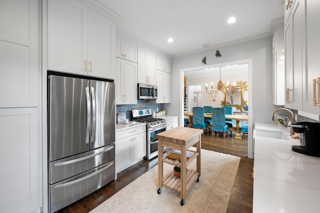 kitchen with appliances with stainless steel finishes, sink, white cabinets, a chandelier, and backsplash