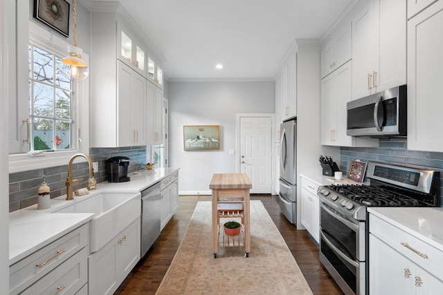 kitchen featuring stainless steel appliances, white cabinetry, pendant lighting, and decorative backsplash