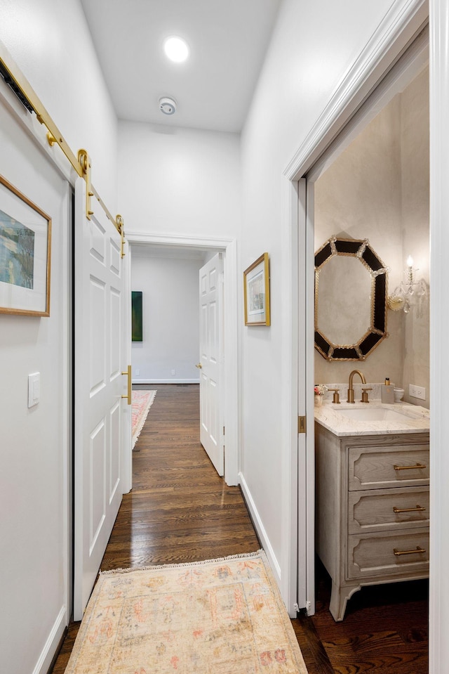 corridor featuring sink, dark hardwood / wood-style floors, and a barn door