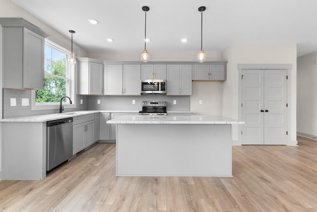 kitchen with decorative light fixtures, gray cabinets, a center island, and appliances with stainless steel finishes