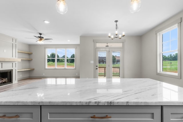 kitchen with wood-type flooring, light stone countertops, gray cabinetry, and decorative light fixtures