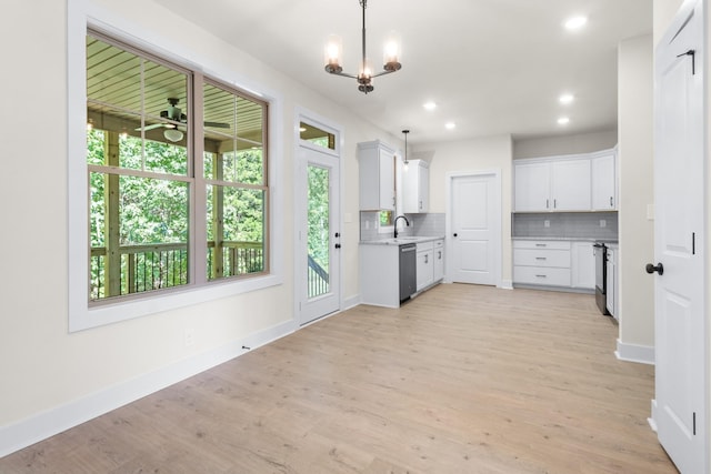 kitchen with appliances with stainless steel finishes, hanging light fixtures, white cabinets, decorative backsplash, and light wood-type flooring