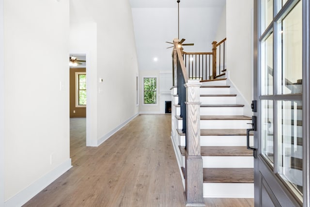 foyer entrance with high vaulted ceiling, ceiling fan, and light hardwood / wood-style flooring