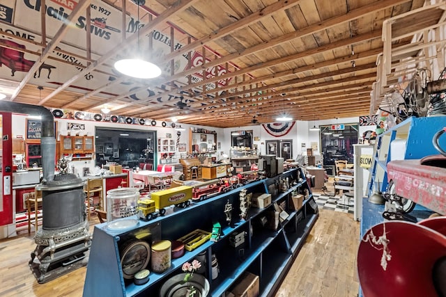 miscellaneous room featuring hardwood / wood-style flooring, a wood stove, wood ceiling, and beam ceiling