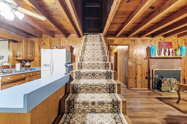 staircase featuring wood walls, sink, hardwood / wood-style flooring, wood ceiling, and beam ceiling