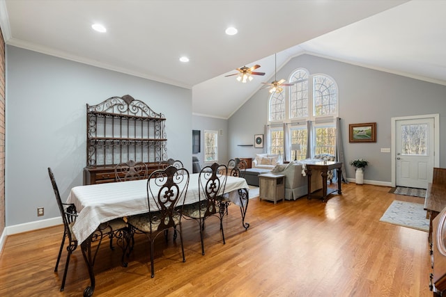 dining room with crown molding, high vaulted ceiling, ceiling fan, and light hardwood / wood-style flooring