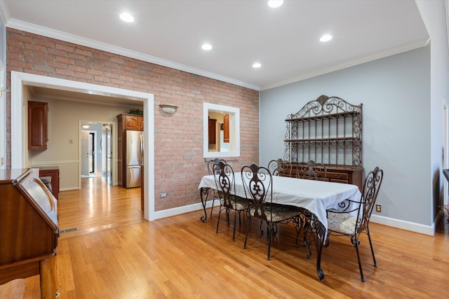 dining room with crown molding, brick wall, and light wood-type flooring