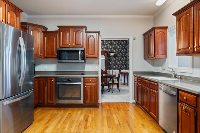 kitchen featuring sink, crown molding, appliances with stainless steel finishes, dark stone counters, and light hardwood / wood-style floors