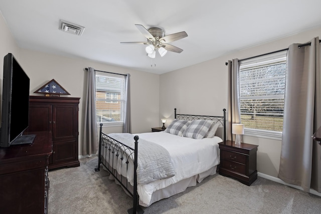 bedroom with multiple windows, light colored carpet, and ceiling fan