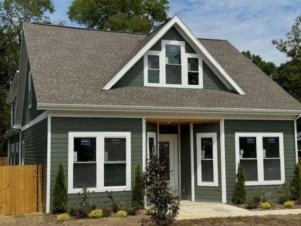 view of front of home with fence, a porch, and roof with shingles