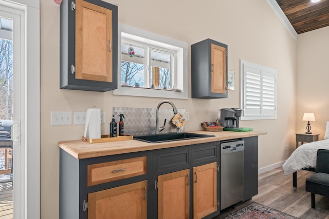 kitchen featuring lofted ceiling, sink, ornamental molding, stainless steel dishwasher, and light hardwood / wood-style floors