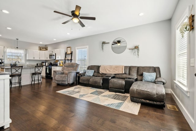 living room with dark wood-type flooring, ceiling fan, and sink