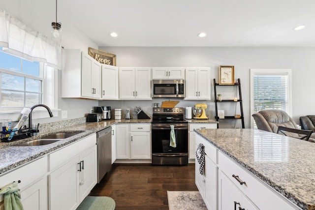 kitchen with stainless steel appliances, decorative light fixtures, sink, and white cabinets