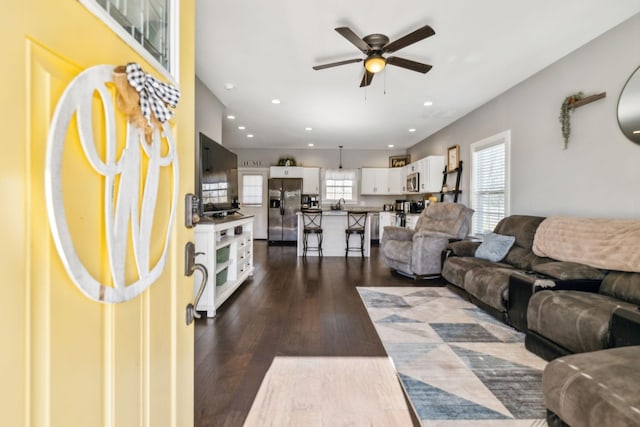 living room featuring dark wood-type flooring, ceiling fan, and sink