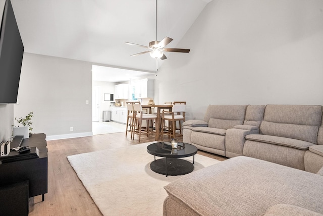 living room featuring ceiling fan, vaulted ceiling, and light wood-type flooring