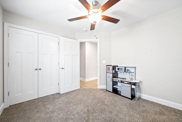 unfurnished bedroom featuring light colored carpet, ceiling fan, and a closet