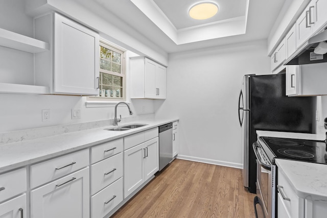 kitchen with sink, white cabinetry, stainless steel appliances, a tray ceiling, and light hardwood / wood-style floors