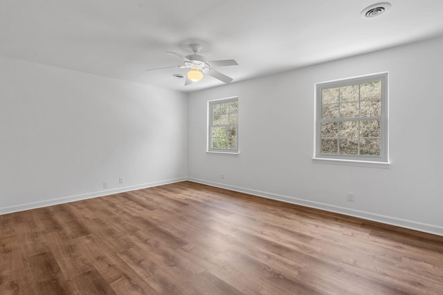 empty room featuring hardwood / wood-style flooring, a healthy amount of sunlight, and ceiling fan