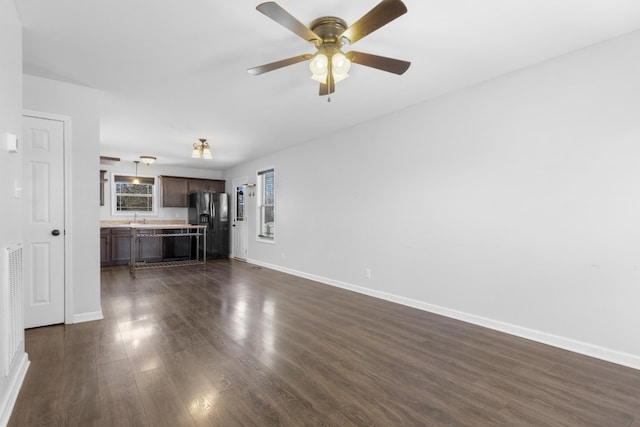 unfurnished living room featuring dark wood-type flooring, ceiling fan, and sink