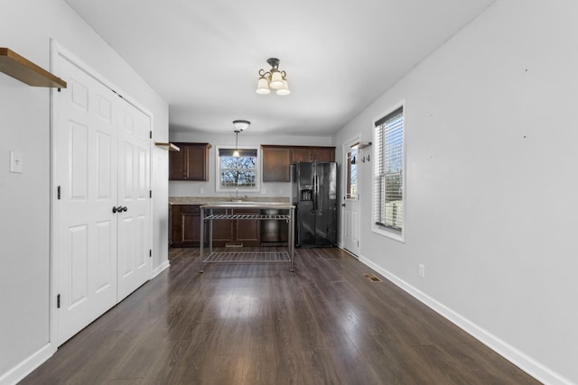 kitchen featuring sink, decorative light fixtures, black refrigerator with ice dispenser, dark brown cabinets, and dark hardwood / wood-style floors