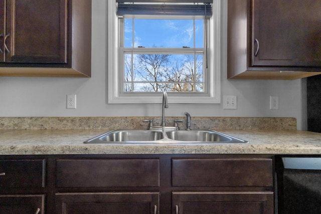 kitchen with black dishwasher, sink, and dark brown cabinets