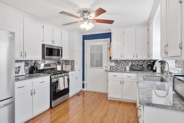 kitchen with sink, light stone counters, appliances with stainless steel finishes, light hardwood / wood-style floors, and white cabinets