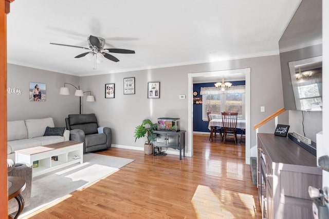 living room with crown molding, ceiling fan with notable chandelier, and light wood-type flooring