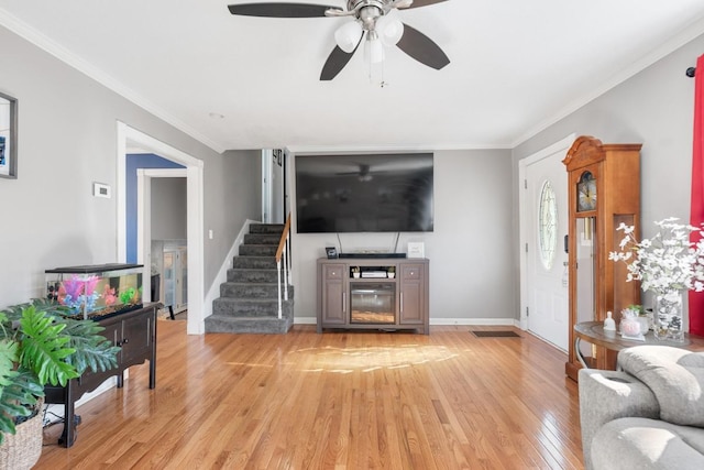 living room featuring crown molding, a fireplace, and light wood-type flooring