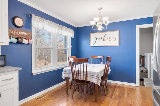 dining room with an inviting chandelier, crown molding, and light hardwood / wood-style floors