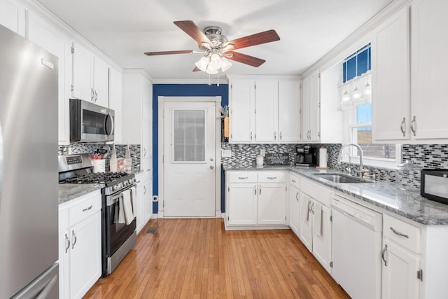 kitchen featuring sink, white cabinetry, light stone counters, stainless steel appliances, and light hardwood / wood-style floors