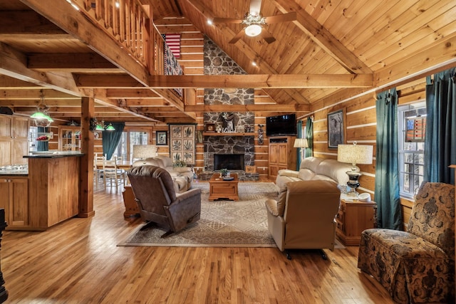 living room with wood walls, beamed ceiling, ceiling fan, wooden ceiling, and light wood-type flooring