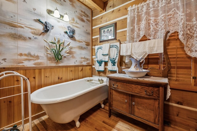 bathroom with a tub to relax in, wood-type flooring, vanity, and wood walls