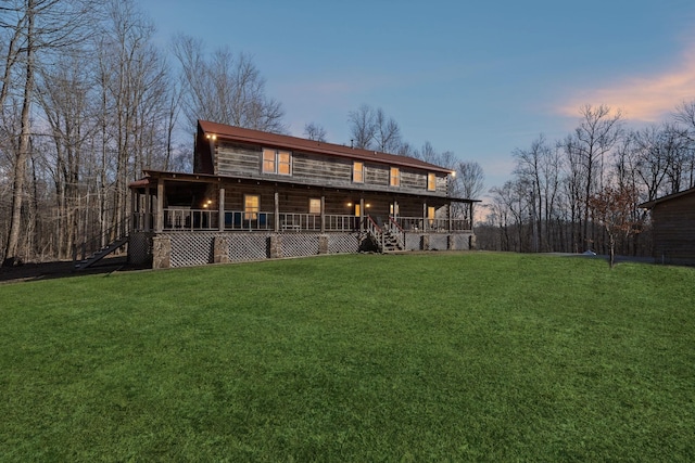 back house at dusk featuring a lawn