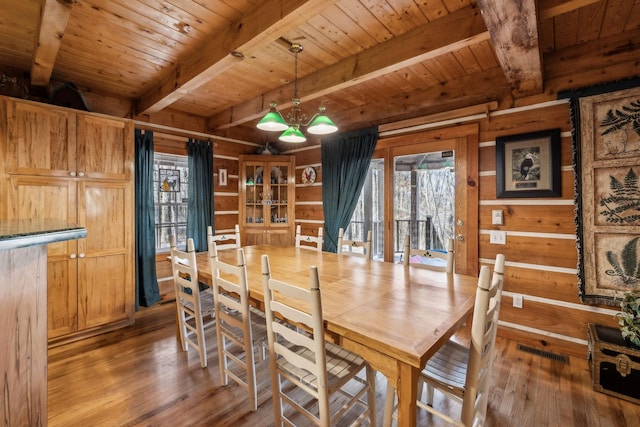 dining space with beamed ceiling and wood-type flooring